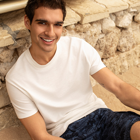 Model trägt weißes T-Shirt und Shorts