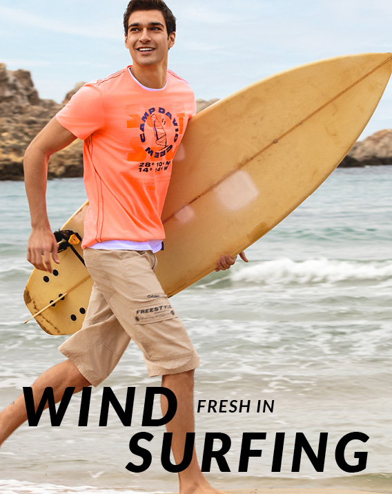 Model trägt T-Shirt und hält ein Surfbrett in der Hand