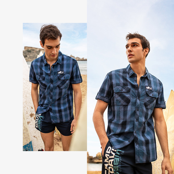 Model trägt Hemd und Badehose am Strand
